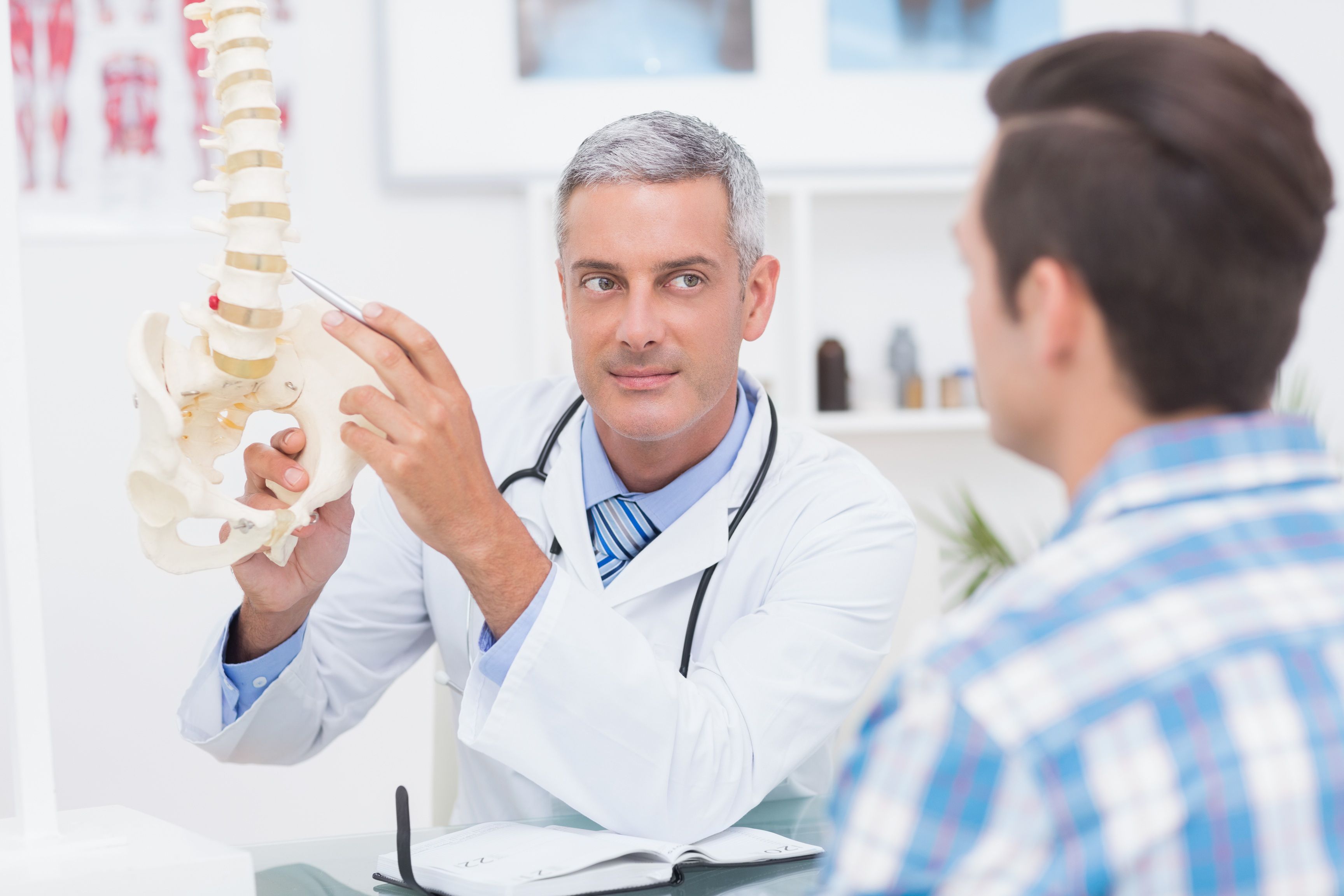 Arts legt iets uit aan patiënt aan de hand van een skelet