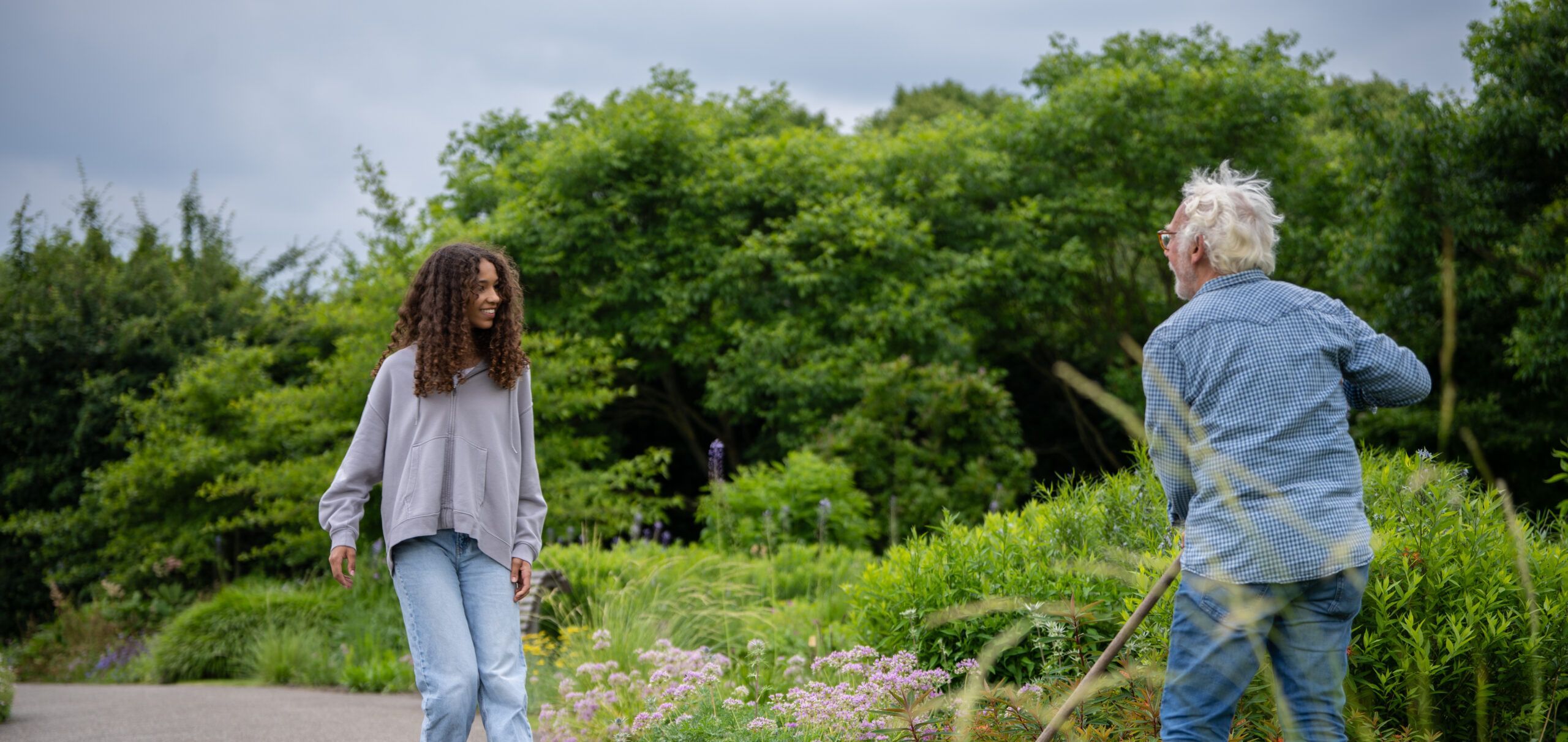 Meisje maakt een praatje met een oudere man in moestuin