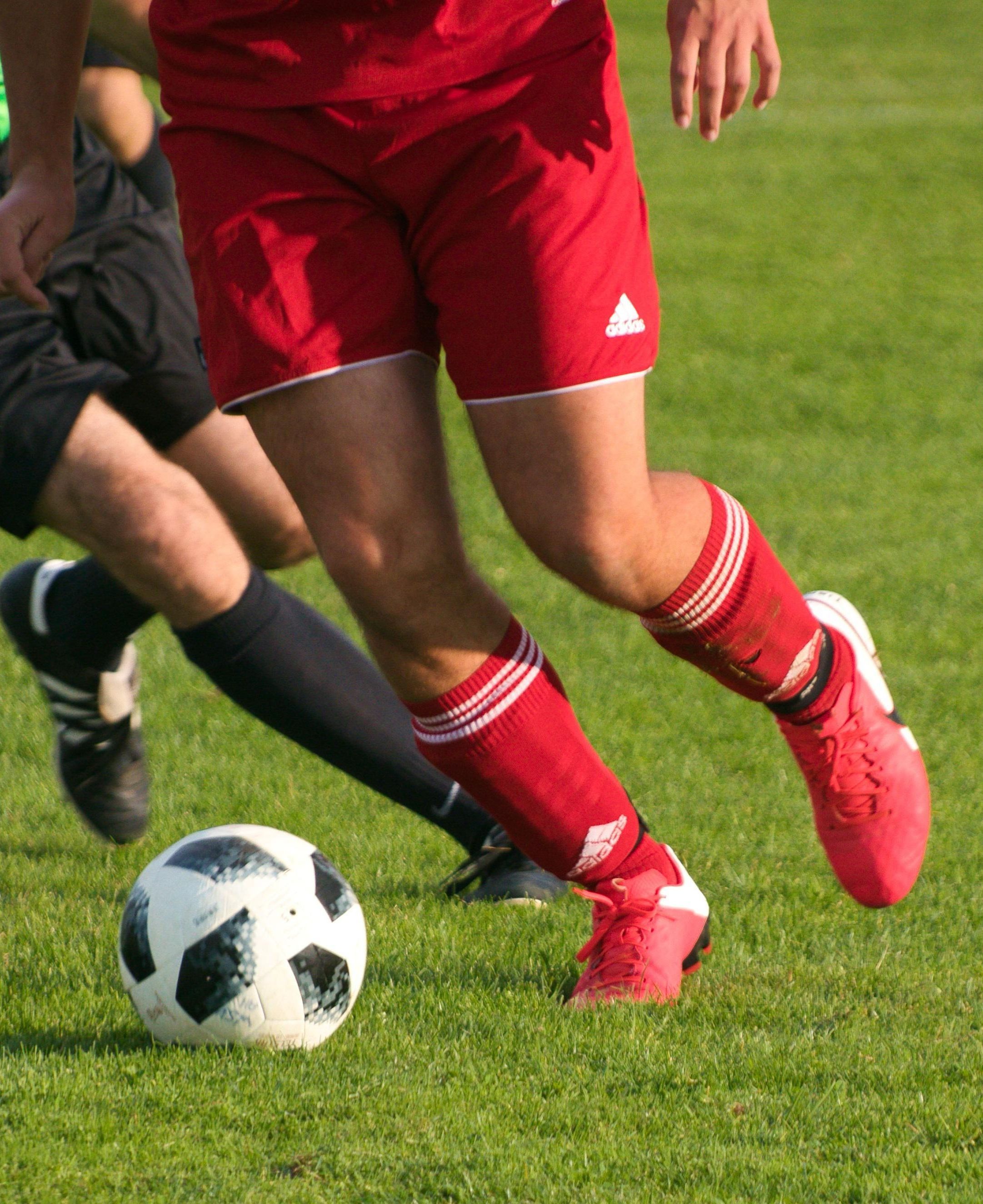 Voeten van voetballers met een bal